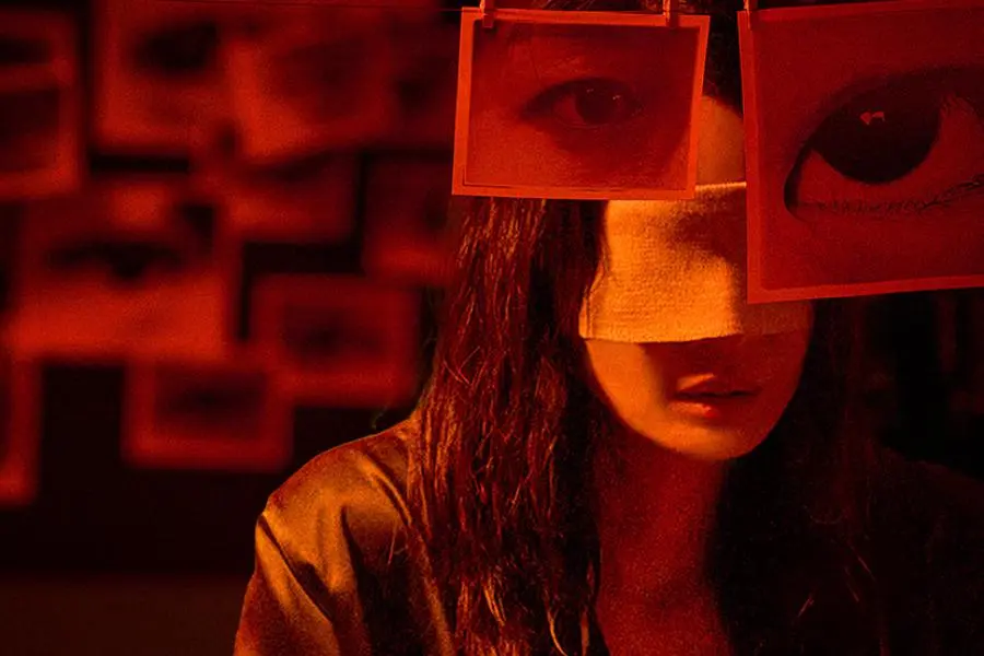 شين مين آه محاطة بعدد لا يحصى من العيون وهي معصوبة العينين في ملصق فيلم "العيون - The Eyes"